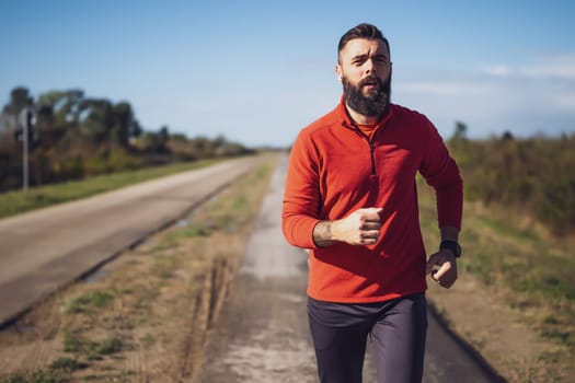 Adult man is jogging outdoor on sunny day.