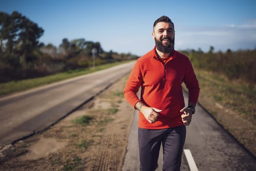 Adult man is jogging outdoor on sunny day.