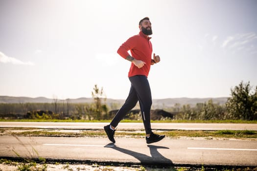 Adult man is jogging outdoor on sunny day.