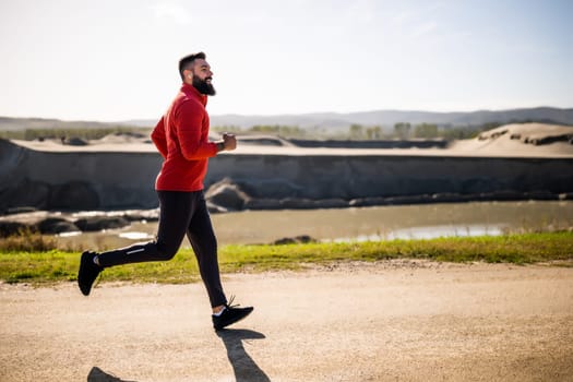 Adult man is jogging outdoor on sunny day.