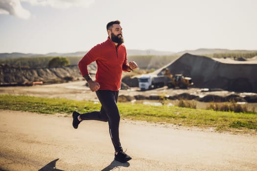 Adult man is jogging outdoor on sunny day.