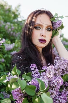 A fashionable girl with dark hair, a spring portrait in lilac tones in summer. Bright professional makeup