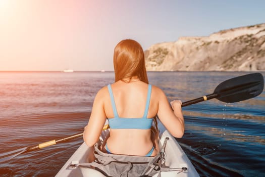 Woman in kayak back view. Happy young woman with long hair floating in transparent kayak on the crystal clear sea. Summer holiday vacation and cheerful female people relaxing having fun on the boat