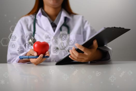 Female doctor with stethoscope holding red heart shape. Medical, health insurance and cardiology concept.