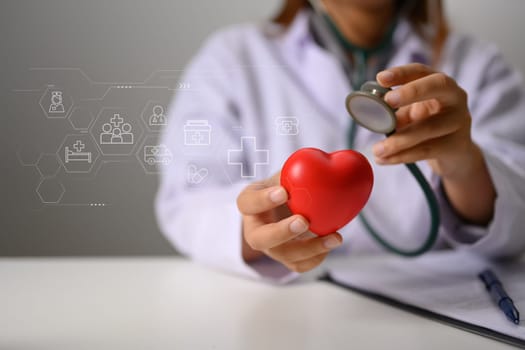 Hands of doctor holding stethoscope and red heart. Health insurance and cardiology concept.