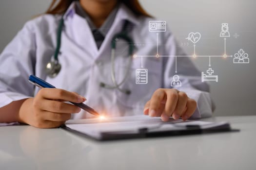 Female doctor with stethoscope recording healthcare treatment at desk.