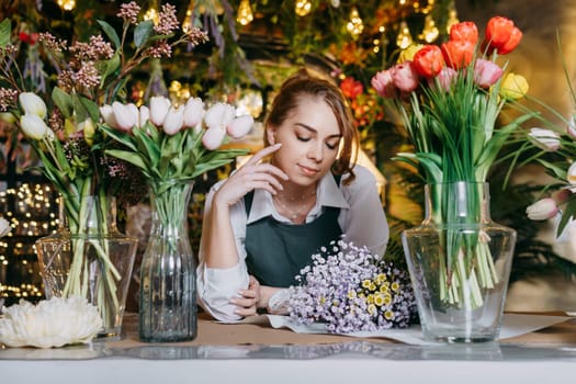 A woman in her florist shop collects bouquets of flowers. The concept of a small business. Bouquets of tulips for the holiday on March 8