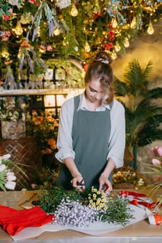 A woman in her florist shop collects bouquets of flowers. The concept of a small business. Bouquets of tulips for the holiday on March 8