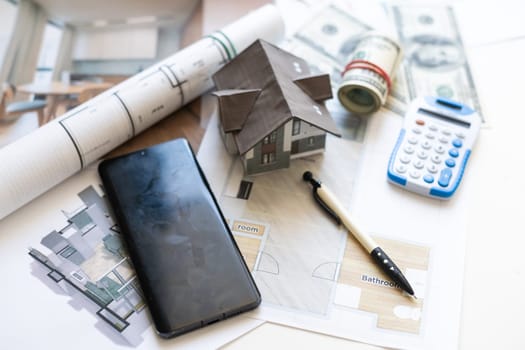 Model house, calculator, cash money and paperwork on a desk: real estate, home loan and investments concept. High quality photo