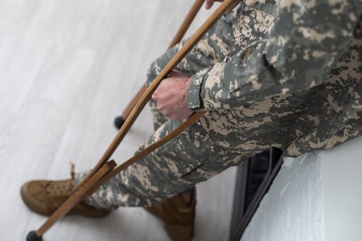 soldier in khaki military uniform on crutches.