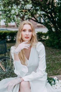 A blonde girl with long hair on a walk in a spring park. Springtime and blooming apple trees