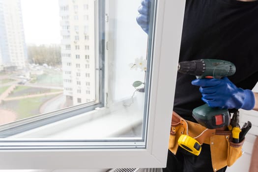 Man in a blue shirt does window installation. High quality photo