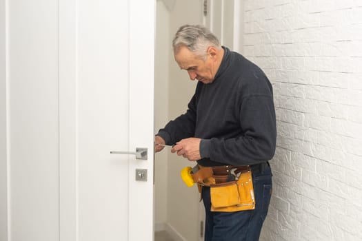 Ordinary elderly man independently repairs a door.