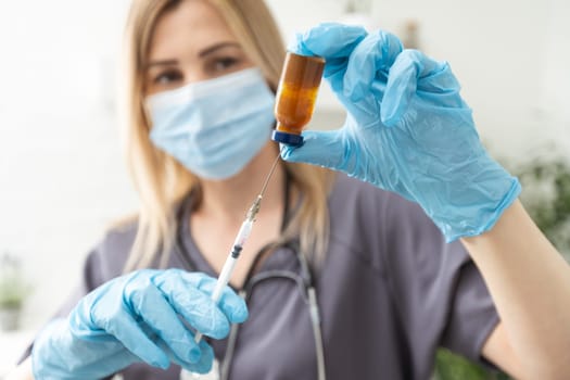 Biological hazard. Epidemic of the Chinese coronavirus. An woman in a protective mask holds an injection syringe and vaccine. Vaccine flu, coronavirus, ebola, TB