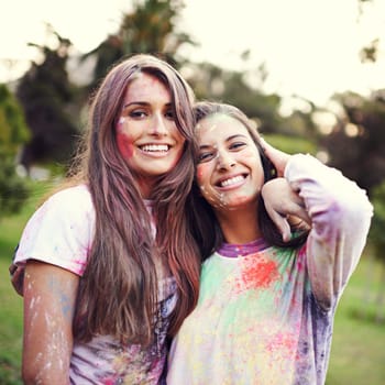 Color, festival and portrait of women with powder together for fun, Holi and outdoor social in spring, nature and joy. Smile, paint splash and celebration in park with friends, trees and happy event.
