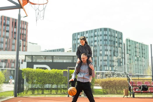 Happy father and teen daughter outside at basketball court