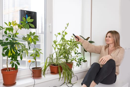 Vacuum cleaner robot cleaning window in high building outdoor. young woman controls the remote