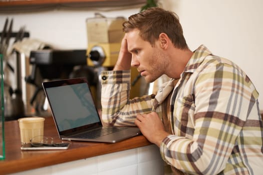 Image of adult man looking complicated at laptop screen, staring puzzled at his monitor, doing difficult task online, sitting in cafe, drinking coffee and working.