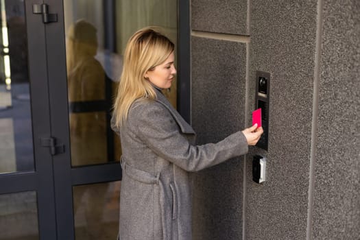 Close up of woman using card intercom at building entrance