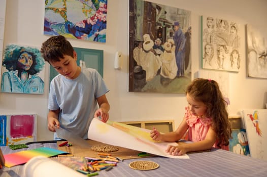Adorable little girl and teenage boy drawing picture in the art class