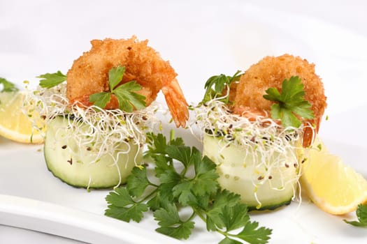 Cucumber appetizer with fried breaded shrimp on a bed of microgreens