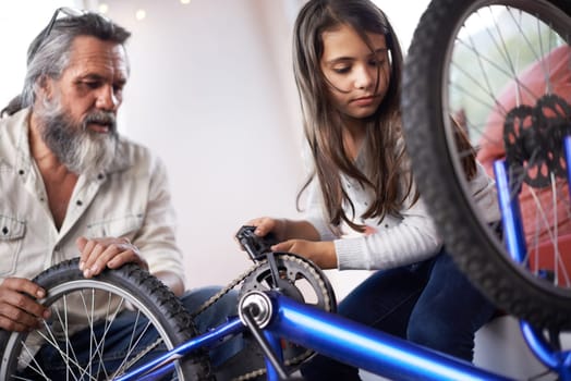 Father, child and bicycle for fixing chain as maintenance in garage for bonding together, transportation or teamwork. Mature man, daughter and equipment for bike repair or gear help, wheel or tyre.