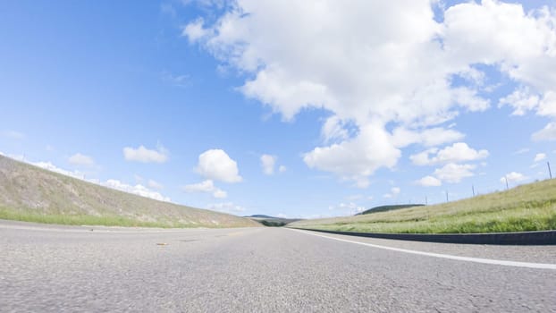 On a clear winter day, a car smoothly travels along Highway 101 near Santa Maria, California, under a brilliant blue sky, surrounded by a blend of greenery and golden hues.