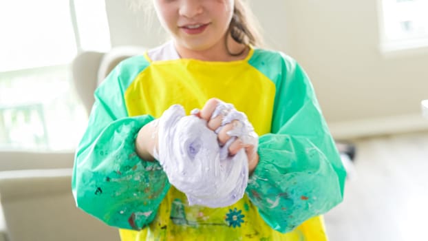 In a modern kitchen, a homeschooled girl is engrossed in creating homemade slime, a fun and educational hands-on project that enhances her creativity and problem-solving skills.