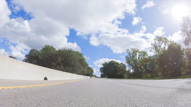 On a clear winter day, a car smoothly travels along Highway 101 near Santa Maria, California, under a brilliant blue sky, surrounded by a blend of greenery and golden hues.