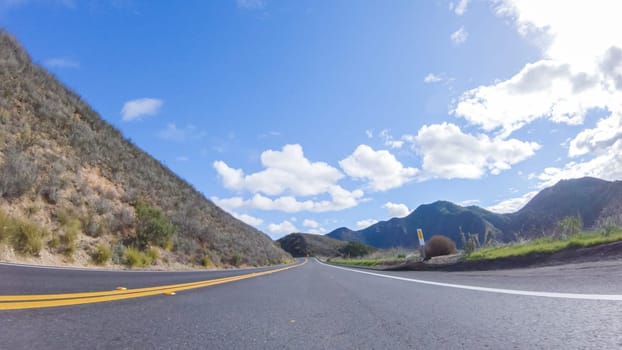 Vehicle is cruising along the Cuyama Highway under the bright sun. The surrounding landscape is illuminated by the radiant sunshine, creating a picturesque and inviting scene as the car travels through this captivating area.