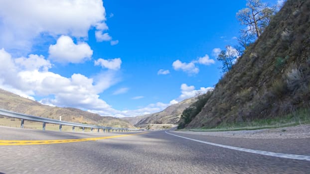 Vehicle is cruising along the Cuyama Highway under the bright sun. The surrounding landscape is illuminated by the radiant sunshine, creating a picturesque and inviting scene as the car travels through this captivating area.