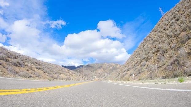 Vehicle is cruising along the Cuyama Highway under the bright sun. The surrounding landscape is illuminated by the radiant sunshine, creating a picturesque and inviting scene as the car travels through this captivating area.