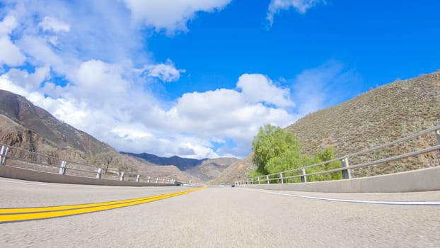 Vehicle is cruising along the Cuyama Highway under the bright sun. The surrounding landscape is illuminated by the radiant sunshine, creating a picturesque and inviting scene as the car travels through this captivating area.