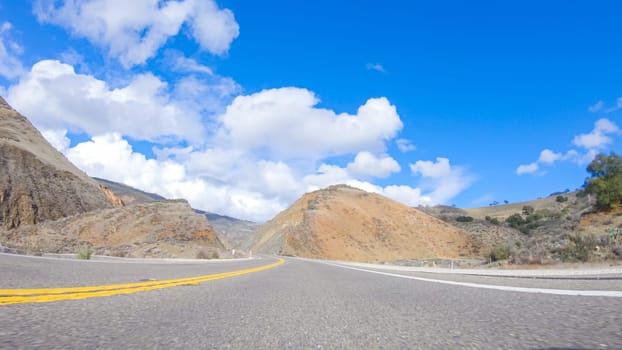 Vehicle is cruising along the Cuyama Highway under the bright sun. The surrounding landscape is illuminated by the radiant sunshine, creating a picturesque and inviting scene as the car travels through this captivating area.