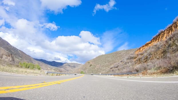 Vehicle is cruising along the Cuyama Highway under the bright sun. The surrounding landscape is illuminated by the radiant sunshine, creating a picturesque and inviting scene as the car travels through this captivating area.