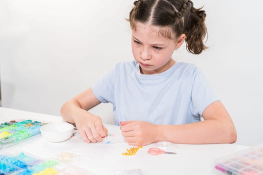 Little girl enjoys crafting colorful bracelets with vibrant clay beads set.