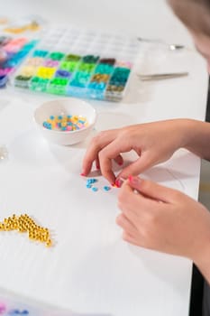 Little girl enjoys crafting colorful bracelets with vibrant clay beads set.