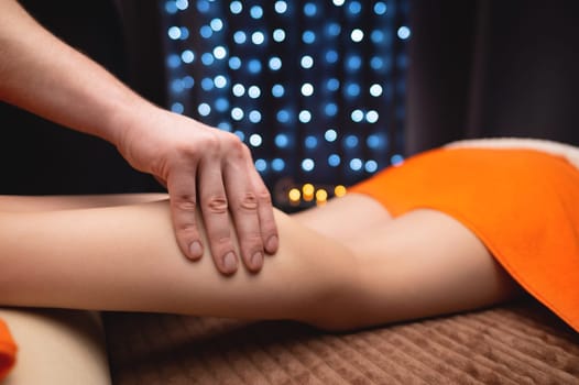 A woman is given a relaxing massage with essential oils, a man massage therapist kneads her thighs with his hands, anti-cellulite procedures.