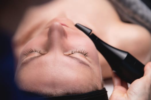 Lymphatic drainage massage is a hardware process. A cosmetologist-therapist gives a model a rejuvenating facial massage in a beauty salon. Close-up.