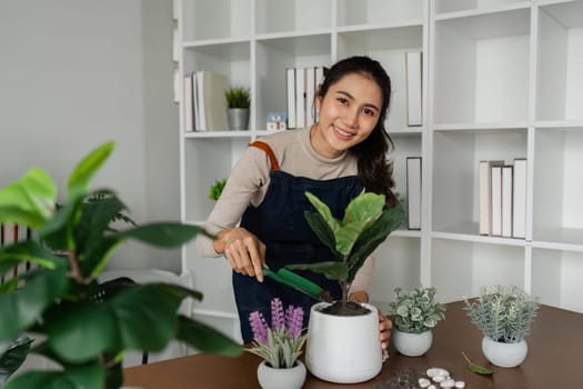 Woman looking at camera while putting plants in pots, doing hobby.