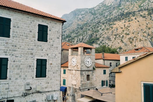 Ancient clock tower among stone houses on the square. Kotor, Montenegro. High quality photo
