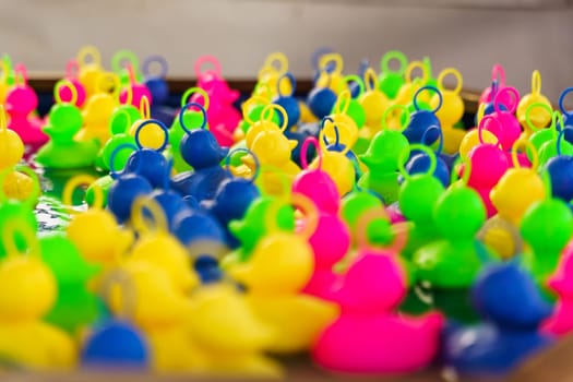 Plastic multi-colored toy ducks float in the water. Children's game of catching ducks with a hook