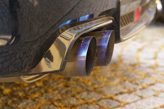 Detailed view of the exhaust pipes on a car, showing the metal material, heat discoloration, and intricate design.
