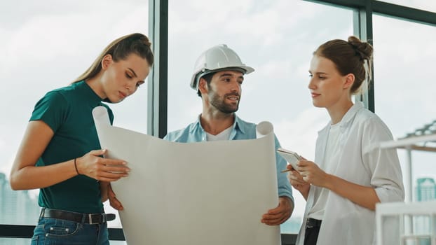 Professional architect engineer team talking, sharing, brainstorming about design while manager hold at project plan. Young architect holding plan while manager listen and point at plan. Tracery