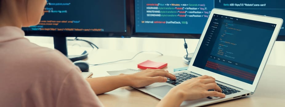 Cropped image of female web developer coding on laptop while computer displayed program and software code at modern office. Close up businesswoman hand focus on analysis data. Burgeoning.