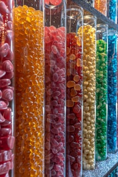 Glass flasks with colorful delicious candies on the shelf.