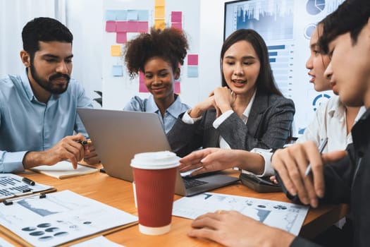 Multiracial analyst team use BI dashboard data to analyze financial report on meeting table. Group of diverse business people utilize data analysis by FIntech for success business marketing. Concord