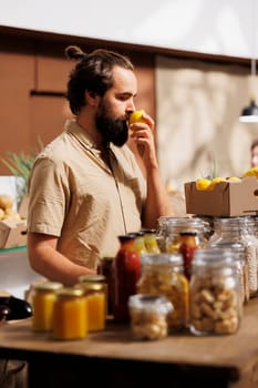 Man in zero waste store smells lemons, making sure they are handpicked and farm grown. Green living customer thoroughly checking local supermarket food items are chemicals free