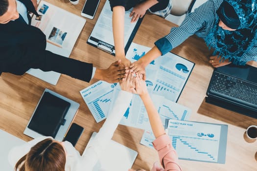 Businessmen and businesswomen joining hands in group meeting at multicultural office room showing teamwork, support and unity in business. Diversity workplace and corporate people working concept. uds