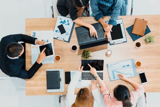 Top view of businessman executive in group meeting with other businessmen and businesswomen in modern office with laptop computer, coffee and document on table. People corporate business team uds